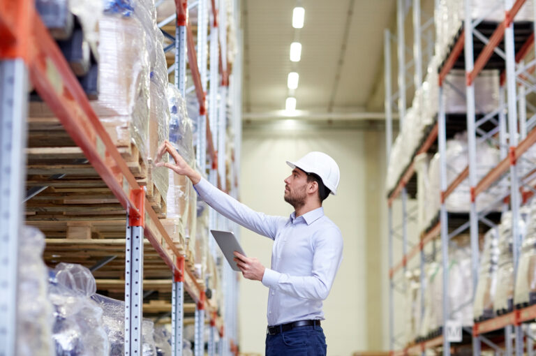 man wearing a hardhat in a warehouse, inspecting inventory